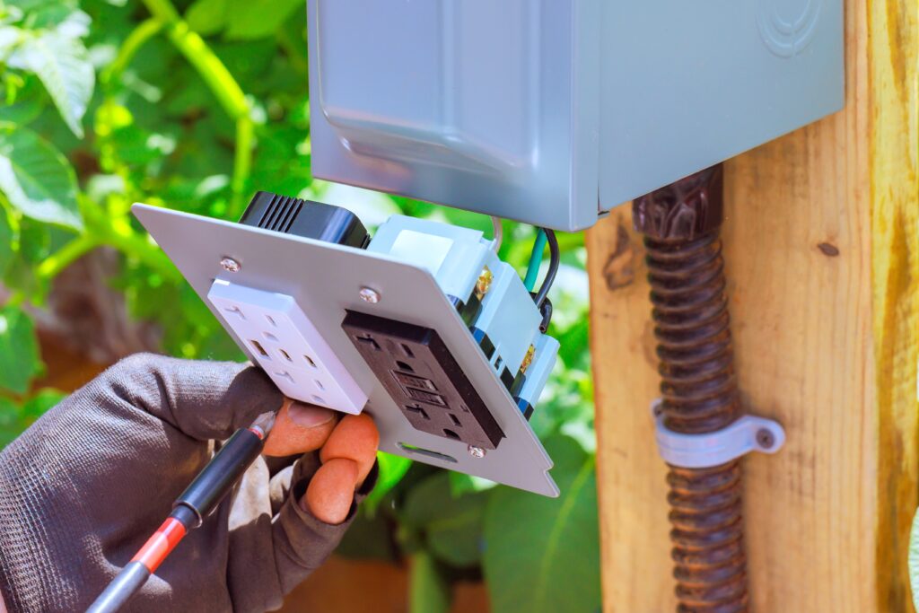 a professional replacing an outdoor outlet on a residential property as part of holiday home safety inspection

